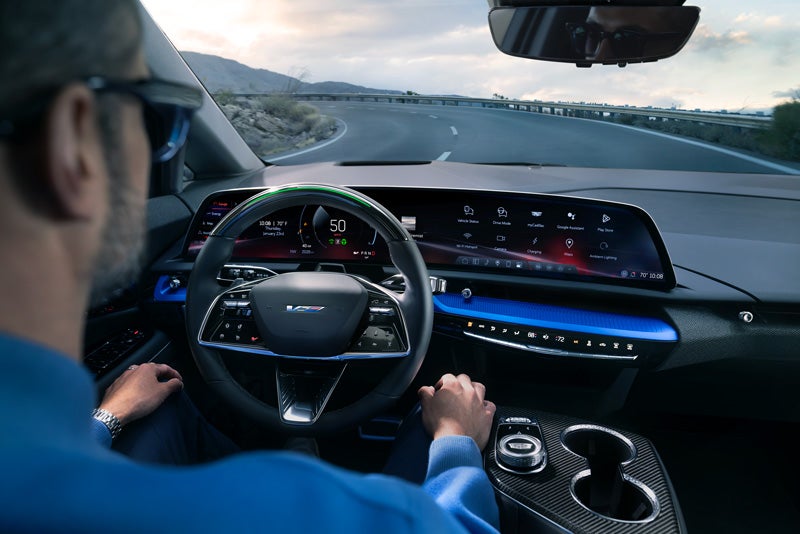 Front View of the 2026 OPTIQ-V Driving Through the Dusk Utilizing its Headlights | Alexandria Cadillac in ALEXANDRIA MN