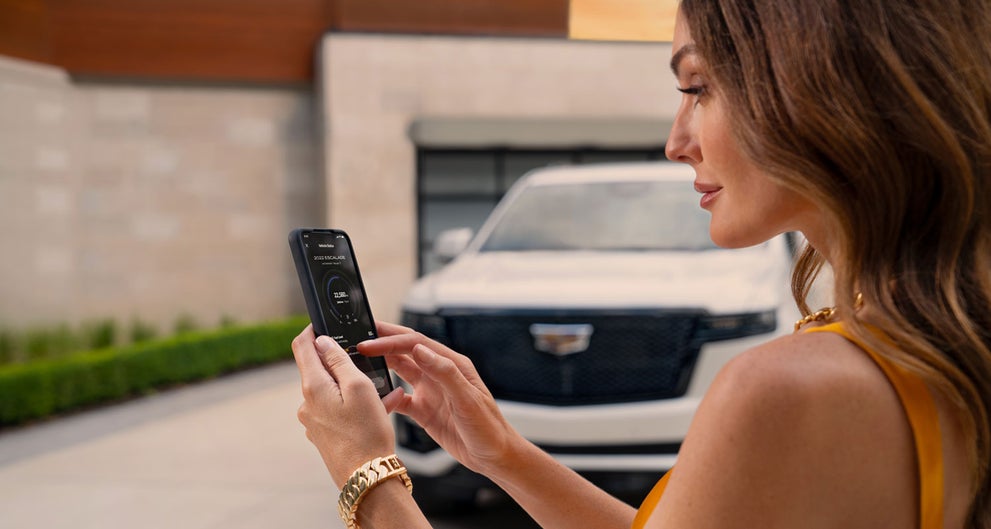 lady checking her mobile with a Cadillac vehicle background | Alexandria Cadillac in ALEXANDRIA MN